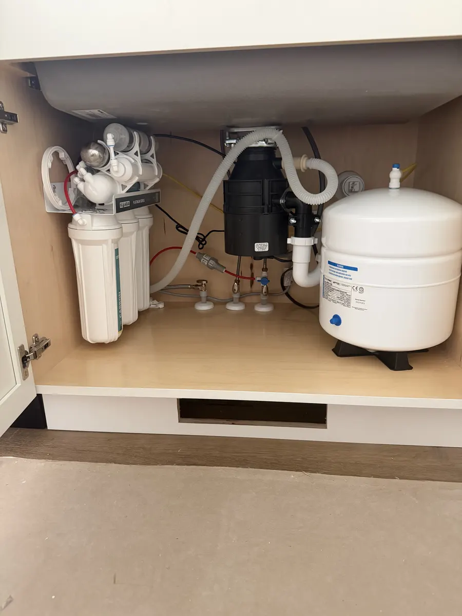 Installed under-sink drinking water filters and storage tank inside a kitchen cabinet