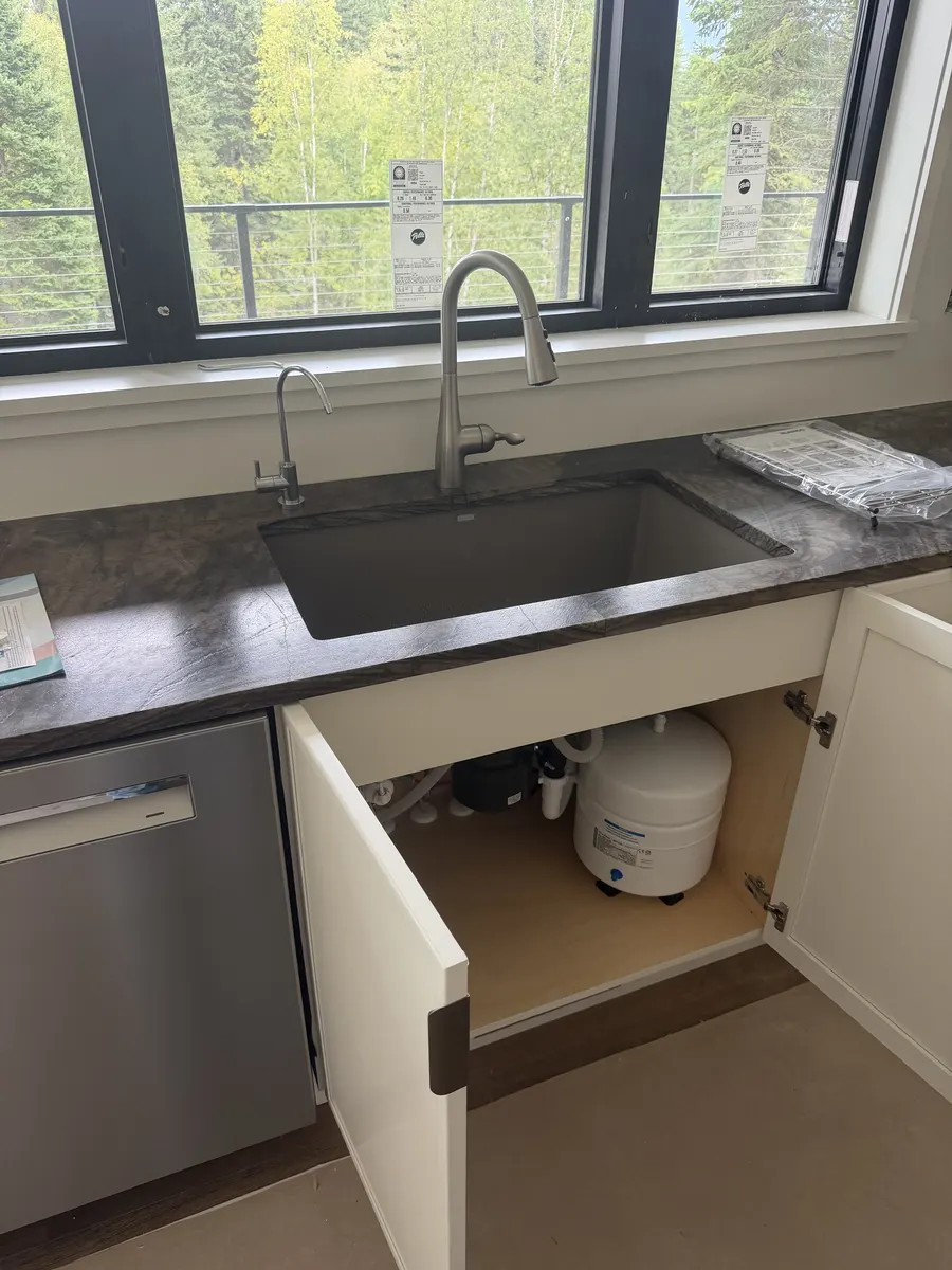 Kitchen sink with an under-sink drinking water filtration tank visible in the open cabinet